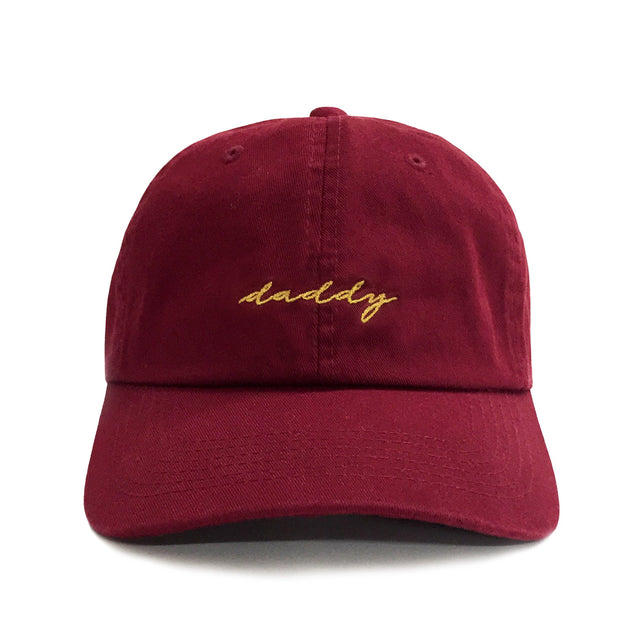 Daddy Hat – Maroon 6-panel cotton dad hat with gold embroidered “Daddy” script, adjustable strap, lightweight and comfortable gift for dads.